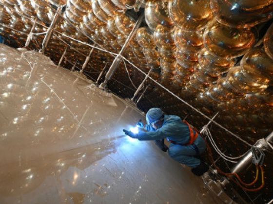 A worker peers into JUNO’s central detector, a hollow sphere filled with 20 000 tons of liquid scintillator. (Photo by Yuexiang Liu, IHEP.) A worker peers into JUNO’s central detector, a hollow sphere filled with 20 000 tons of liquid scintillator